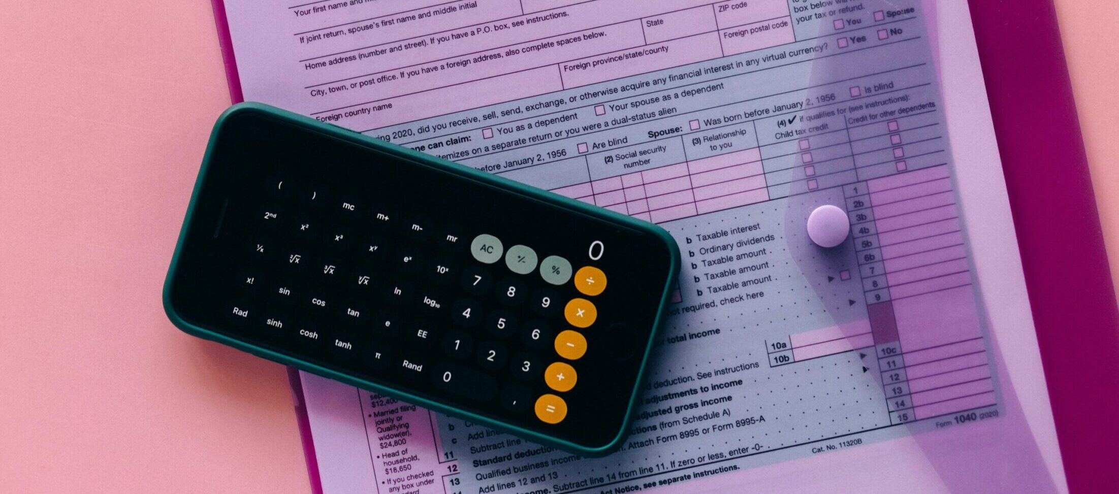 Tax form 1040 with a calculator on a pink background, highlighting finance and accounting themes.